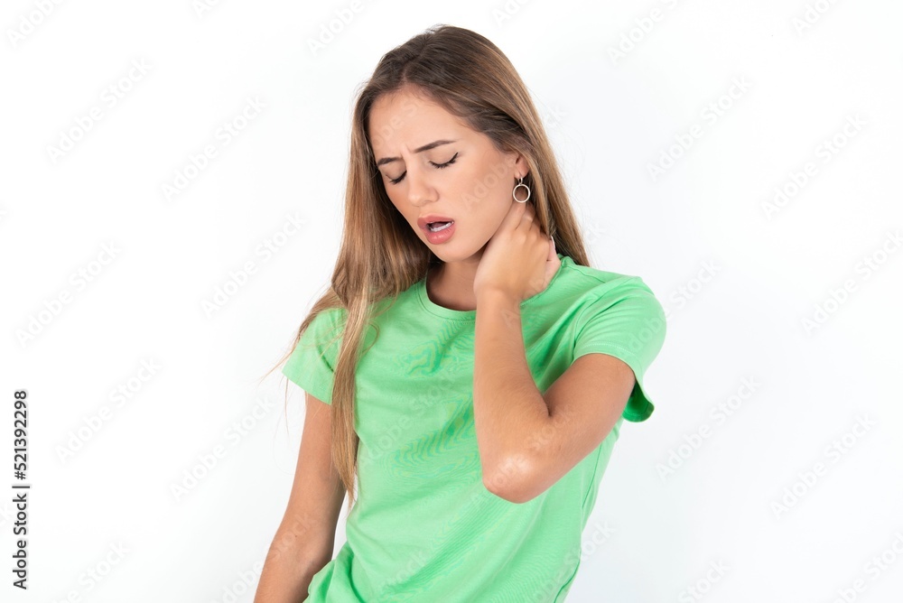 young beautiful woman wearing green T-shirt over white background, Suffering of neck ache injury, touching neck with hand, muscular pain young beautiful woman wearing green T-shirt over white background, Suffering of neck ache injury, touching neck with hand, muscular pain