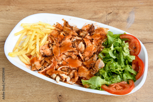 Turkish and Arabic Traditional Ramadan doner kebab with tasty tomato sauce and rice or turkish pilav in white plate on wood table background. ( Pilav ustu doner) photo