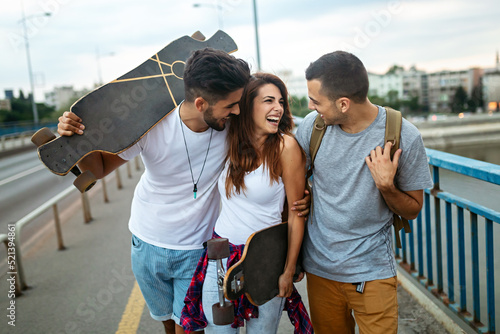Group of happy teen people hang out together and enjoying skateboard outdoors.