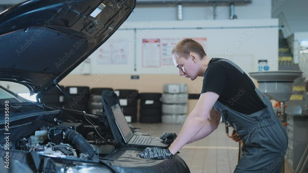 Car maintenance service. The mechanic makes diagnostics of the engine compartment using a computer. Car maintenance service. The mechanic makes diagnostics of the engine compartment using a computer.