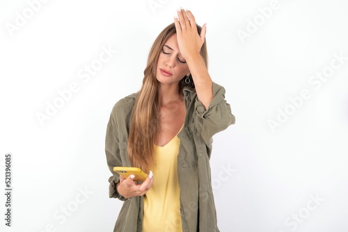 Fotografie Upset depressed young beautiful woman wearing green overshirt over white backgro