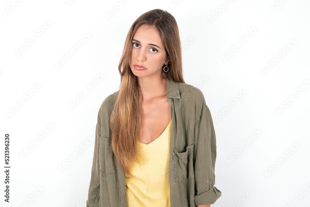 young beautiful woman wearing green overshirt over white background depressed and worry for distress, crying angry and afraid. Sad expression. young beautiful woman wearing green overshirt over white background depressed and worry for distress, crying angry and afraid. Sad expression.