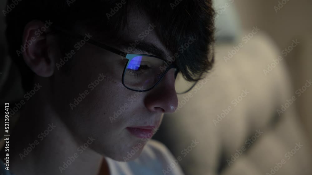 Closeup portrait of cute teenager boy working at night looking at laptop screen, reflected on eyeglasses. Closeup portrait of cute teenager boy working at night looking at laptop screen, reflected on eyeglasses.