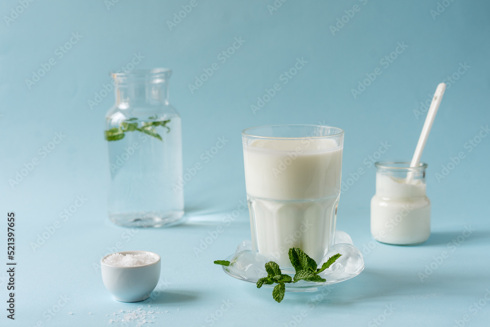 Ayran or Doogh is a popular refreshing Middle Eastern beverage made with yogurt, water and salt. Blue background Ayran or Doogh is a popular refreshing Middle Eastern beverage made with yogurt, water and salt. Blue background