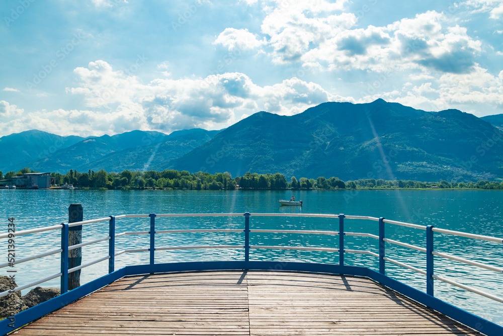 Old wooden jetty on the promenade of Lovere, Lake Iseo, Italy, with turquoise waters. Italian alps on the background, with blue sky and white clouds.