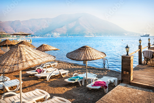 Sunbeds and umbrellas on the sea beach and ship, Marmaris, Turkey