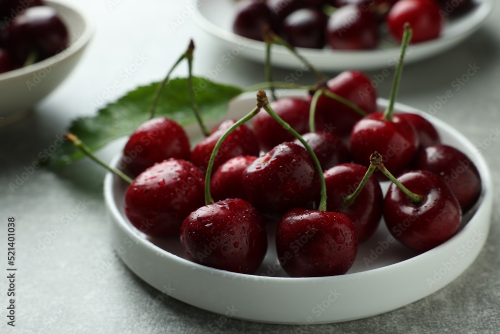 Fresh ripe cherries with water drops on light grey table, closeup Fresh ripe cherries with water drops on light grey table, closeup
