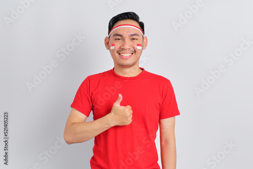 Happy young Asian man celebrating Indonesian independence day showing thumbs up gesture isolated on white background