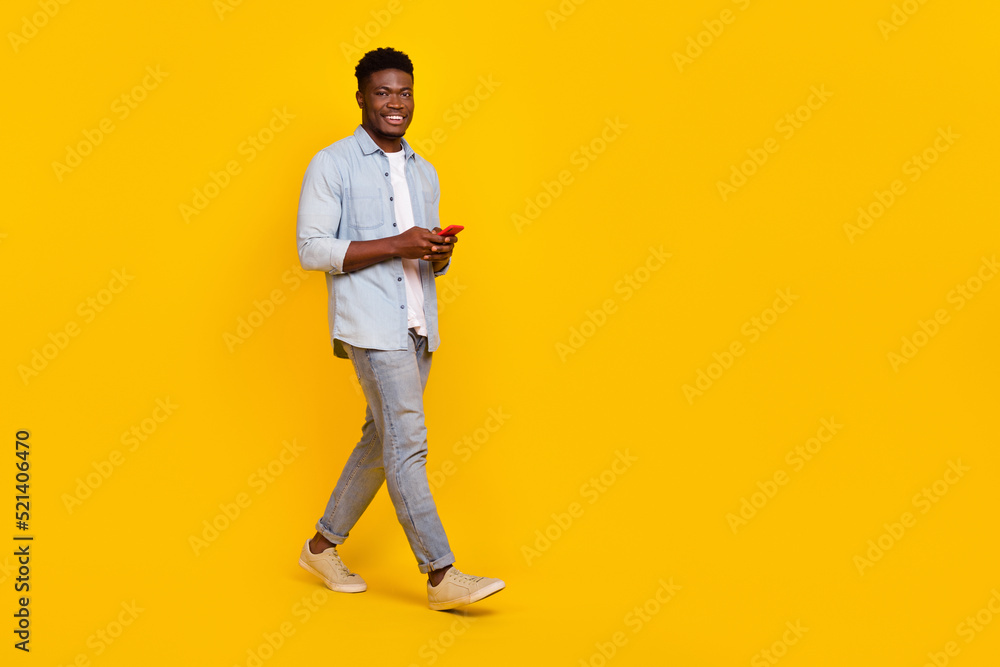 Full size photo of millennial guy walk use smart device communicate blog followers isolated bright color background Full size photo of millennial guy walk use smart device communicate blog followers isolated bright color background