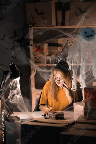 Small business dropshipping. A young businesswoman in a witch costume is sitting in a warehouse taking an order about by phone. Big Sale on Halloween. Banner.