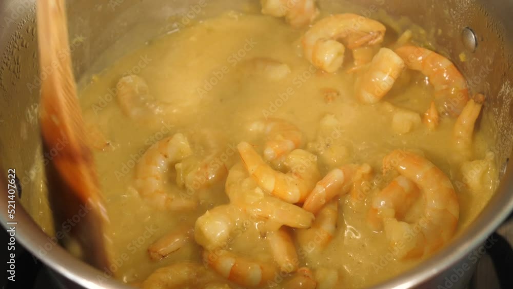 Inside a large pot, chunky coconut-based curry sauce is cooked and stirred inside a pot with a large wooden spoon. Typically Indian or Thai stew. Inside a large pot, chunky coconut-based curry sauce is cooked and stirred inside a pot with a large wooden spoon. Typically Indian or Thai stew.