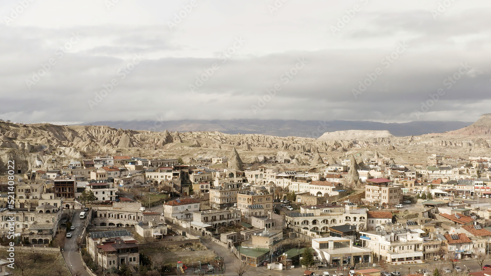 Aerial view of old Cappadocia Park in Turkey. Action. Stone houses and buildings surrounded by rocks on cloudy sky background.