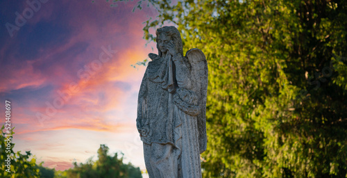 Sculpture of a weeping angel in the old Jewish cemetery in the shade of a tree