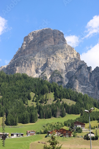 Coravara  Italy-July 16  2022  The italian Dolomites behind the small village of Corvara in summer days with beaitiful blue sky in the background. Green nature in the middle of the rocks. 