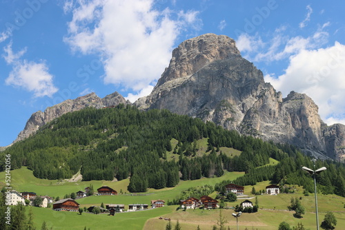 Coravara  Italy-July 16  2022  The italian Dolomites behind the small village of Corvara in summer days with beaitiful blue sky in the background. Green nature in the middle of the rocks. 