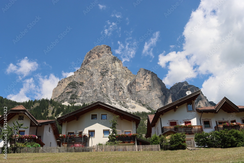 Coravara, Italy-July 16, 2022: The italian Dolomites behind the small village of Corvara in summer days with beaitiful blue sky in the background. Green nature in the middle of the rocks. 