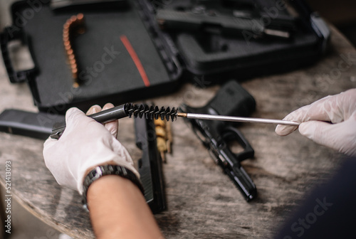The gunsmith is sitting around cleaning the gun and disassembling and maintaining the pistol.