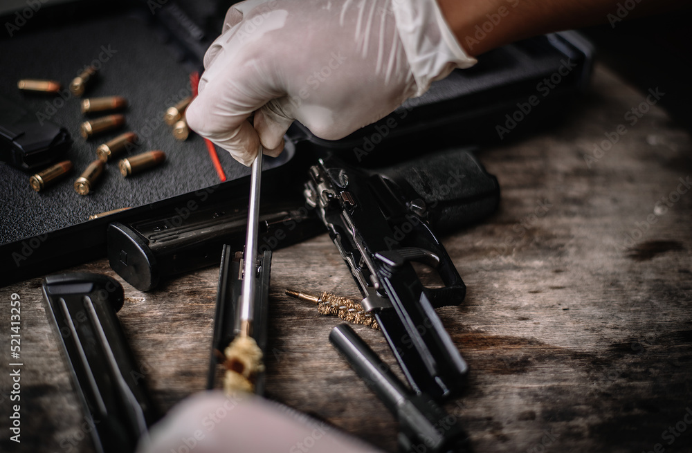 The gunsmith is sitting around cleaning the gun and disassembling and