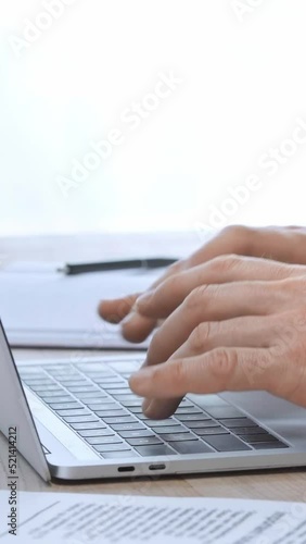 vertical video of cropped businessman typing on laptop keyboard photo
