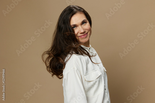 a beautiful horizontal portrait of an adult woman with black hair flowing in the wind standing in a white shirt. Studio photo with an empty space on the background