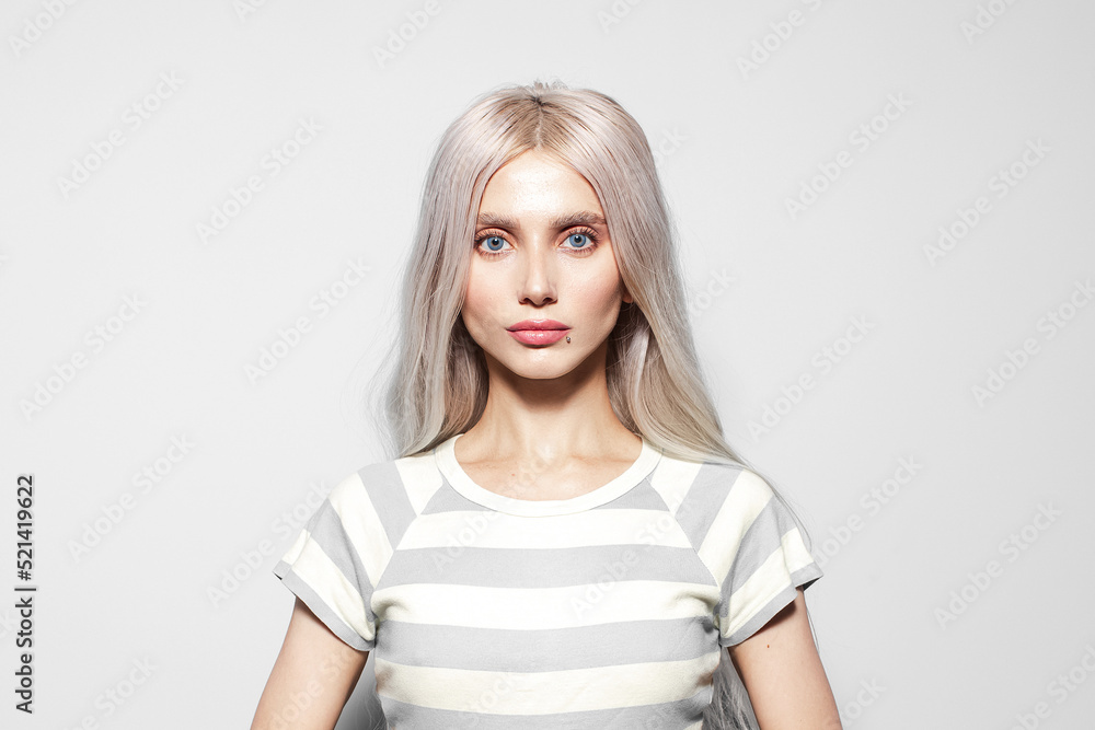 Studio portrait of serious, cute young girl with blonde hair in striped shirt on white background. Studio portrait of serious, cute young girl with blonde hair in striped shirt on white background.