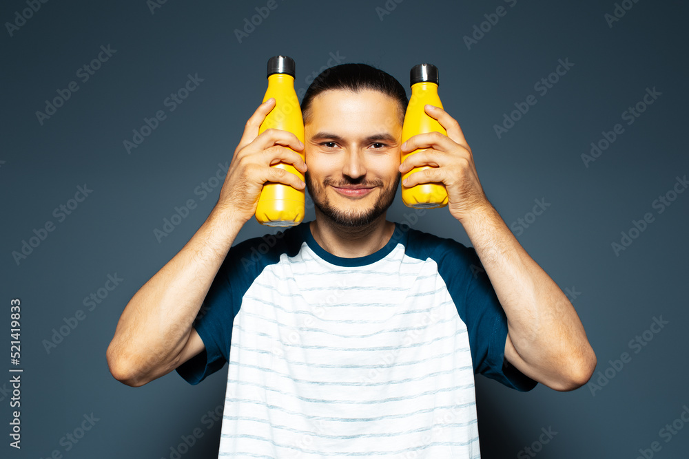 Studio portrait of young joyful man, with two yellow eco bottles in hands. Studio portrait of young joyful man, with two yellow eco bottles in hands.