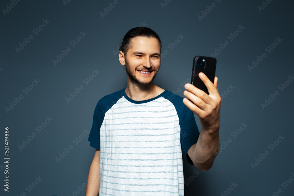 Studio portrait of young smiling man, taking selfie with smartphone. Studio portrait of young smiling man, taking selfie with smartphone.