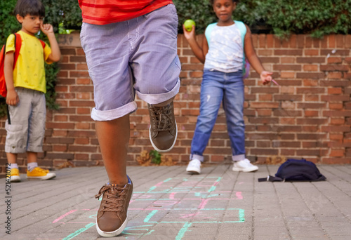 multiethnic kids playing hopscotch on school playground. photo