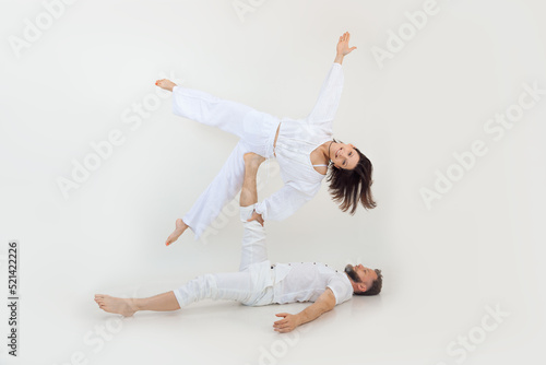 Active, sportive happy family of man and woman practicing yoga as couple. Male hold woman side like star in air on leg.