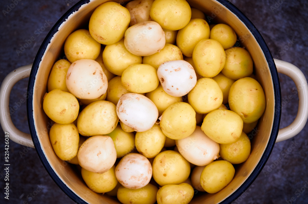 Peeled potatoes in a saucepan on a dark background. Top view. Peeled potatoes in a saucepan on a dark background. Top view.