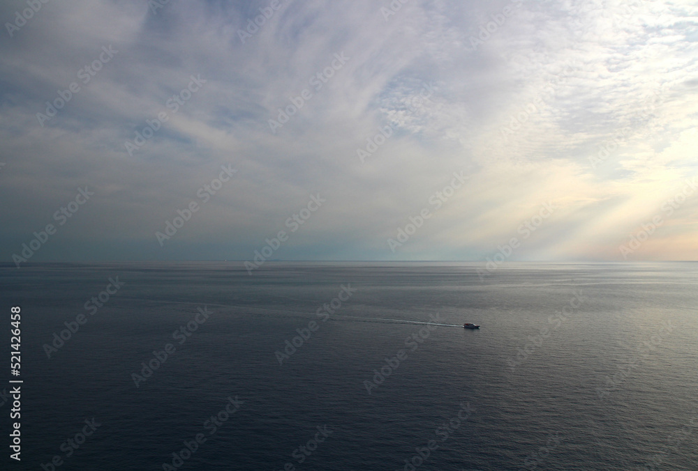 Seen from the heights of Corniglia at the end of an October day (Cinque Terre, Liguria, Italy), a boat returns to port.