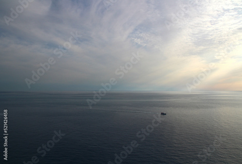 Fototapeta Naklejka Na Ścianę i Meble -  Seen from the heights of Corniglia at the end of an October day (Cinque Terre, Liguria, Italy), a boat returns to port.