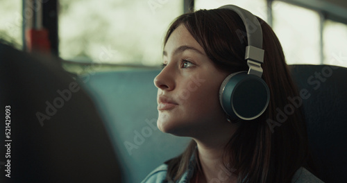 Girl teenager traveling bus with headphones close up. Brunette listening music.