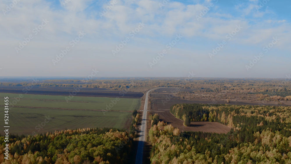 Road between yellow and green autumn forest and fields in Ural Road between yellow and green autumn forest and fields in Ural