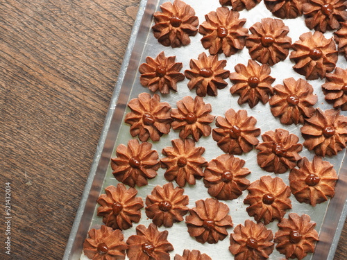 flower shaped cinnamon butter cookies with caramel in baking tray on wooden background