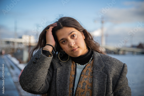 Photography Portrait of a young Moroccan girl outside in winter with thoughtful and worried expression, she touches her hair with her hand