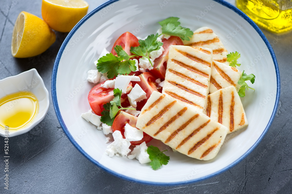 Plate with slices of grilled haloumi cheese, tomato wedges and feta, middle close-up, selective focus Plate with slices of grilled haloumi cheese, tomato wedges and feta, middle close-up, selective focus