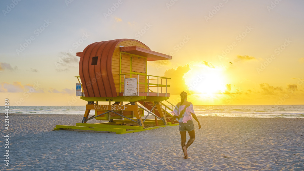 Fototapeta premium South Beach Miami Florida, beach hut lifeguard hut during sunset. beautiful sunset on Miami Beach. Young men walking on the beach during sunset