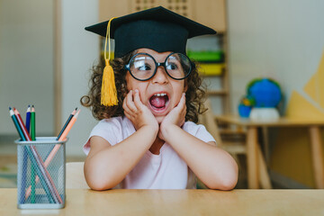 Portrait of happy little girl in graduation mortar hat