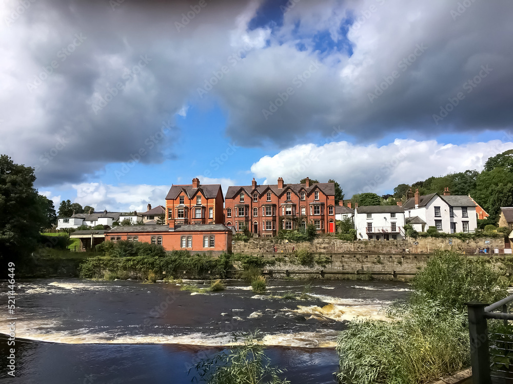 View of the turbulent River Dee and houses in the background. View of the turbulent River Dee and houses in the background.