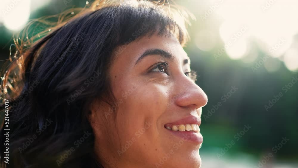Happy South American young woman looking at sky smiling with HOPE standing outside in SUNLIGHT Happy South American young woman looking at sky smiling with HOPE standing outside in SUNLIGHT