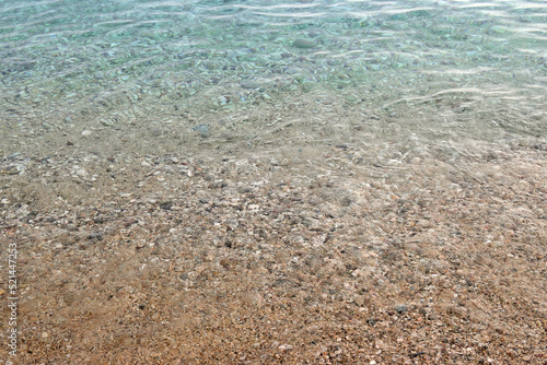 The shore of a pebble beach with clear turquoise water