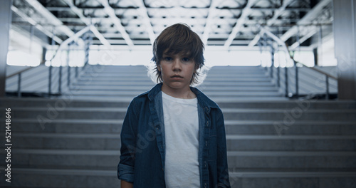 Depressed school boy standing alone at empty staircase close up. Fearful eyes photo