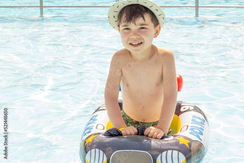 happy joyful little boy having fun in pool water.kid using inflatable ring police car shape.swimming summer time sunshine bright light day.travel tourism s trip vacation family.leisure #521448650
