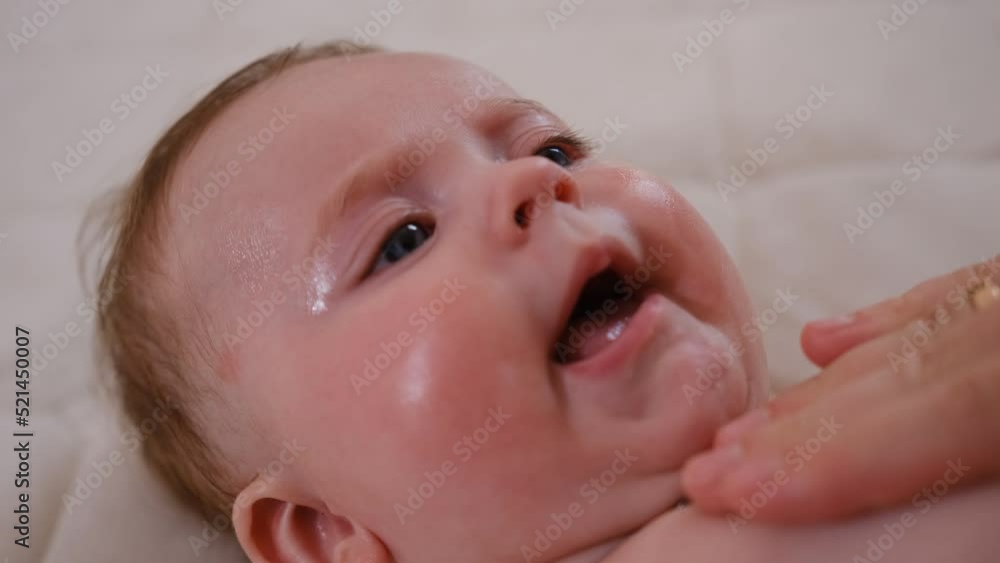 Little baby girl suffering from dermatitis and acne on face skin cured with moisturizing lotion and medical ointment. Concept of newborn baby hygiene, health and skin care. Little baby girl suffering from dermatitis and acne on face skin cured with moisturizing lotion and medical ointment. Concept of newborn baby hygiene, health and skin care.