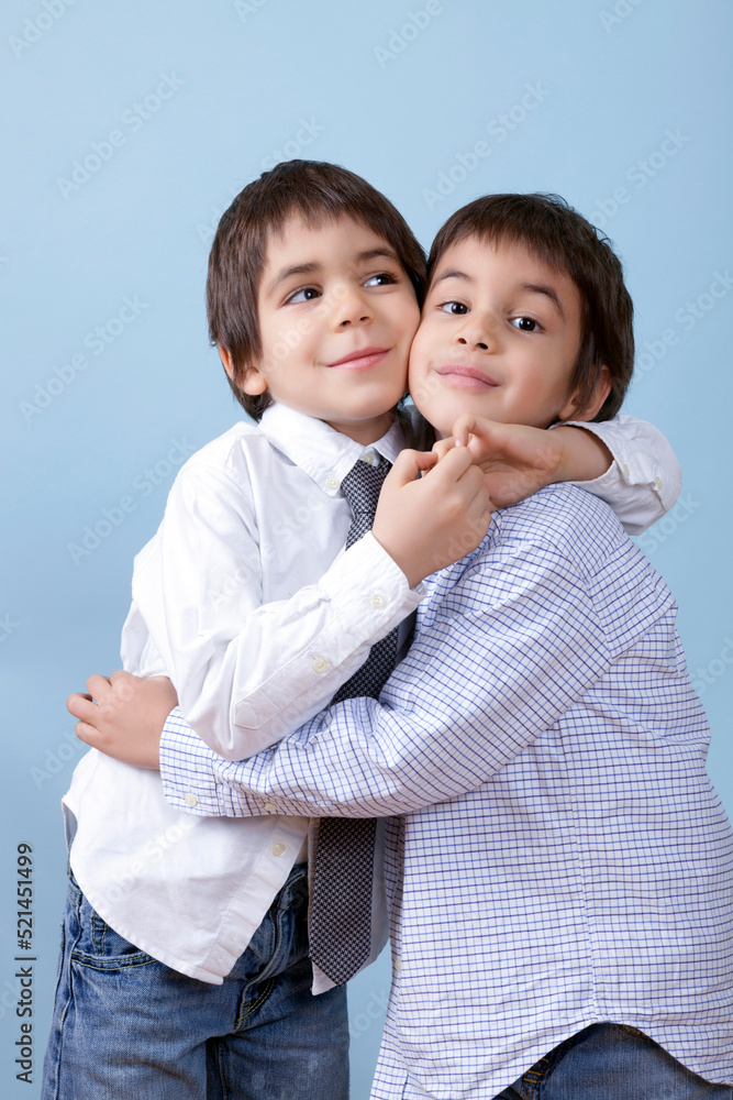 Little Cute Twins Are Holding Eachother Against Blue Little Cute Twins Are Holding Eachother Against Blue