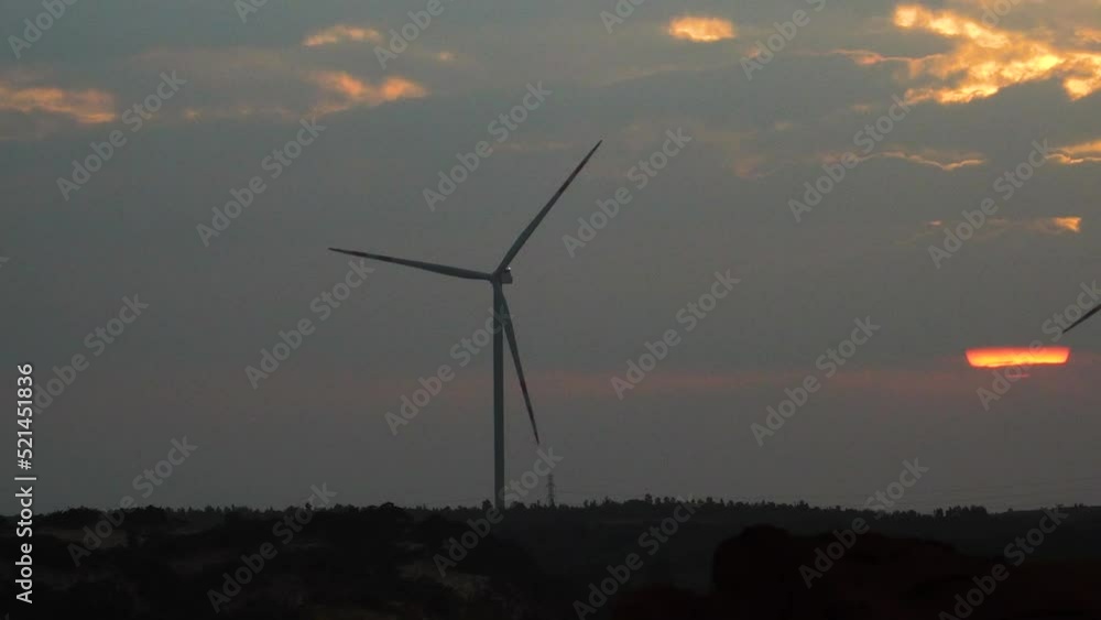 Slow zoom out, silhouette of wind turbines spinning during dusk, generating electricity Slow zoom out, silhouette of wind turbines spinning during dusk, generating electricity