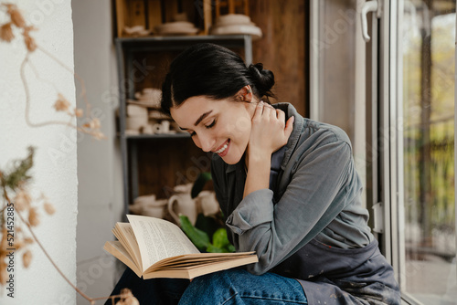 Young beautiful smiling woman reading book and holding her neck