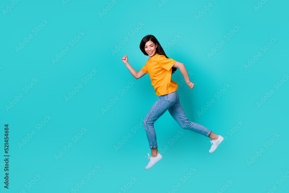 Full size photo of sweet brunette lady run wear orange t-shirt jeans sneakers isolated on teal color background