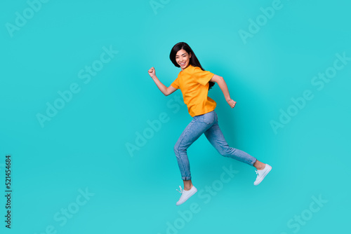 Fototapeta Naklejka Na Ścianę i Meble -  Full size photo of sweet brunette lady run wear orange t-shirt jeans sneakers isolated on teal color background